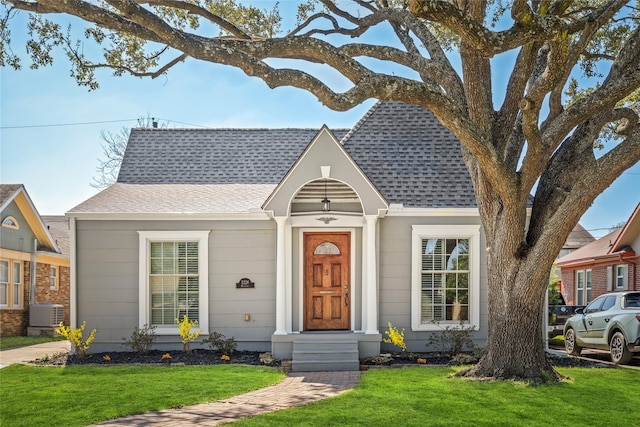 view of front of house with a shingled roof, entry steps, central AC, and a front lawn