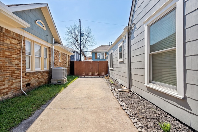 view of property exterior with brick siding, a patio, crawl space, central AC, and fence