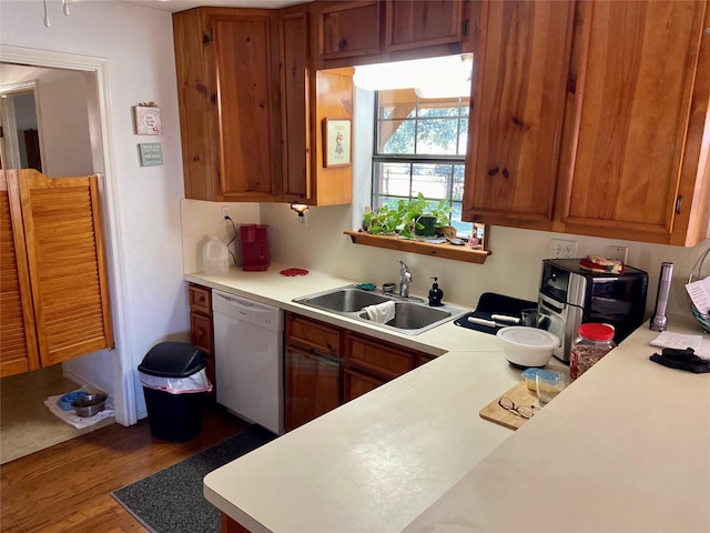 kitchen featuring a sink, brown cabinetry, light countertops, and dishwasher