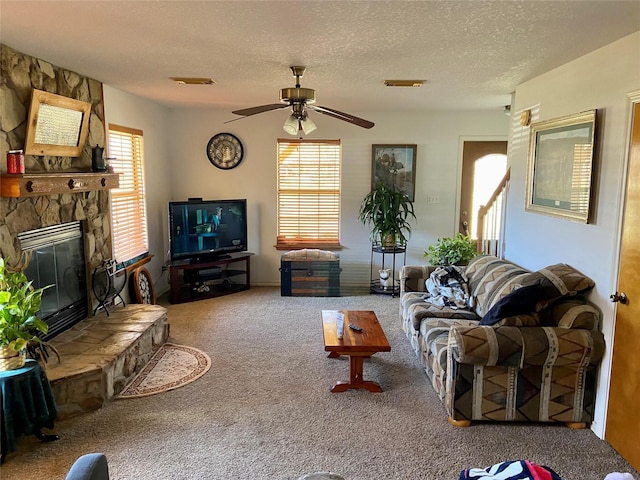 carpeted living room featuring visible vents, a stone fireplace, and a textured ceiling