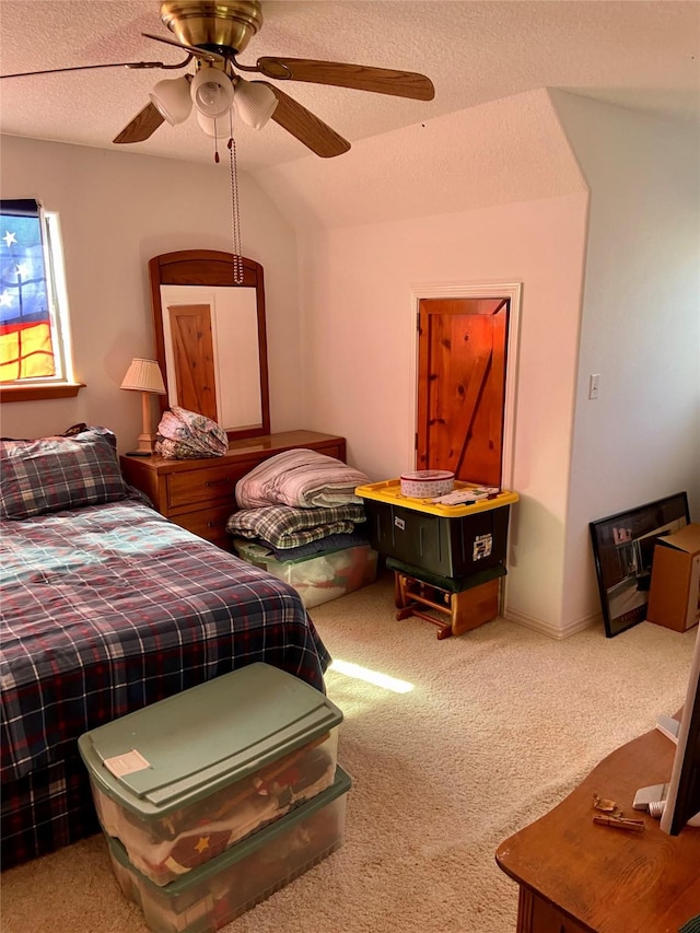 bedroom featuring a ceiling fan, carpet flooring, vaulted ceiling, and a textured ceiling