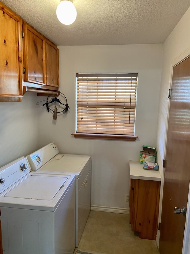 clothes washing area featuring cabinet space, a textured ceiling, baseboards, and washer and dryer