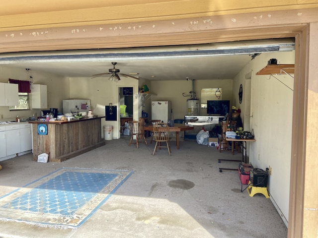 garage featuring water heater, a ceiling fan, and freestanding refrigerator