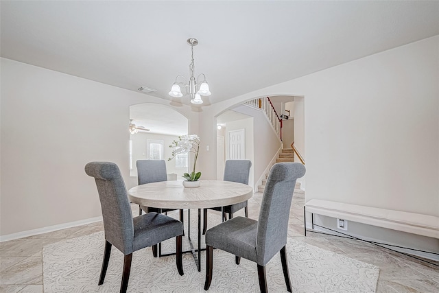 dining area featuring arched walkways, visible vents, stairway, a chandelier, and baseboards