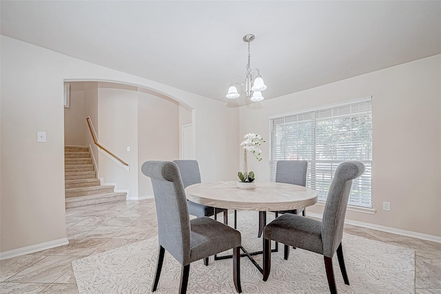 dining area with baseboards, arched walkways, and a chandelier