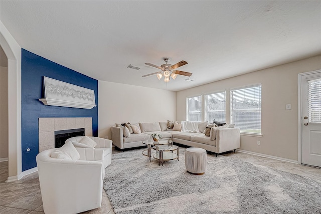 living room with baseboards, a fireplace, visible vents, and a ceiling fan