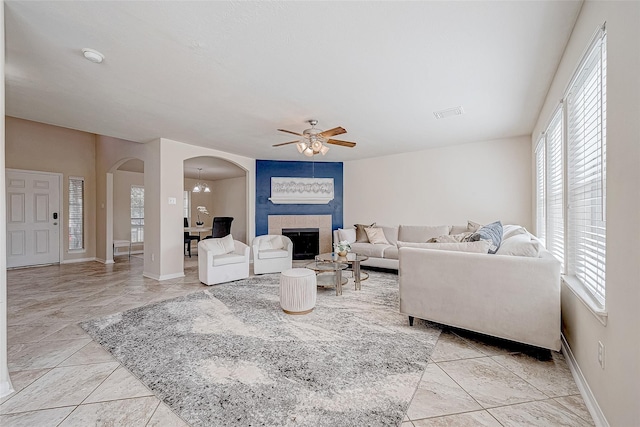 living area featuring visible vents, arched walkways, baseboards, and a tile fireplace