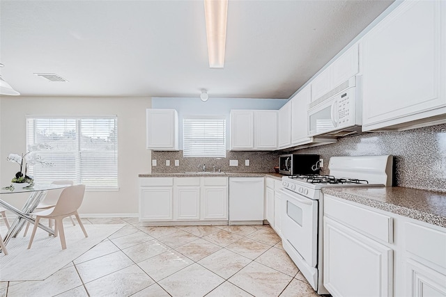 kitchen with light tile patterned floors, white appliances, a sink, white cabinetry, and backsplash