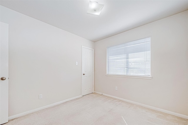 spare room with light carpet and baseboards