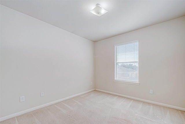 spare room with light carpet and baseboards