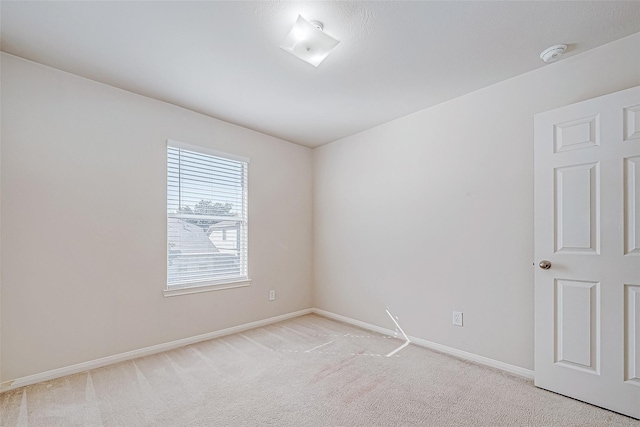 unfurnished room with light carpet and baseboards