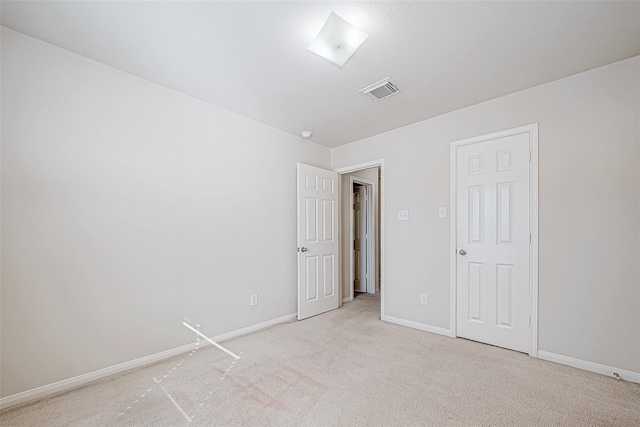 empty room with baseboards, visible vents, and light colored carpet