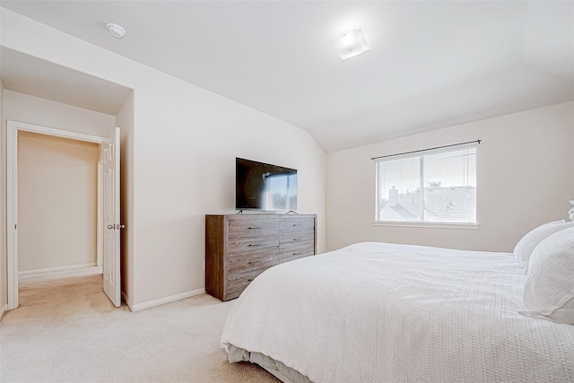 bedroom featuring lofted ceiling, baseboards, and light colored carpet