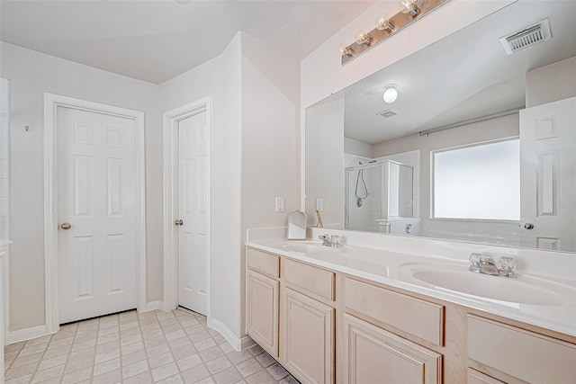 bathroom featuring double vanity, a shower stall, visible vents, and a sink