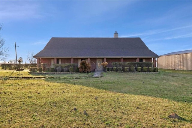 farmhouse featuring brick siding, a chimney, and a front lawn