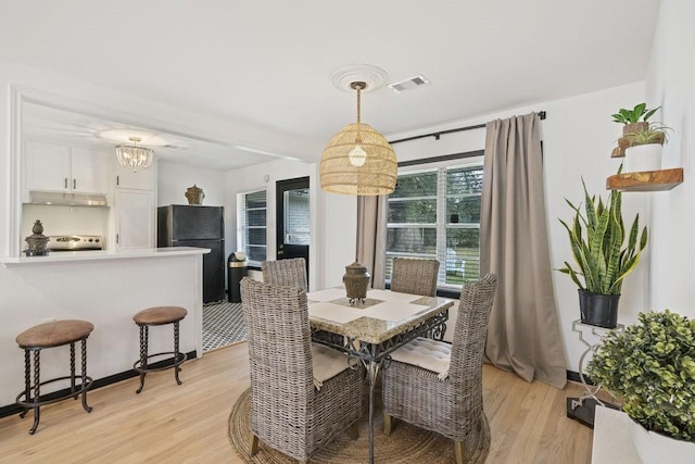 dining space featuring light wood-style flooring and visible vents