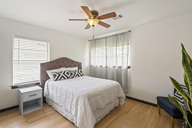 bedroom with visible vents, multiple windows, light wood-style flooring, and baseboards