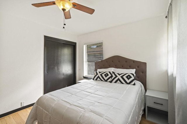 bedroom featuring a closet, wood finished floors, a ceiling fan, and baseboards