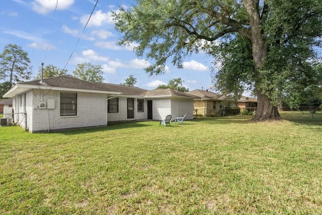 rear view of house with fence, a lawn, and brick siding