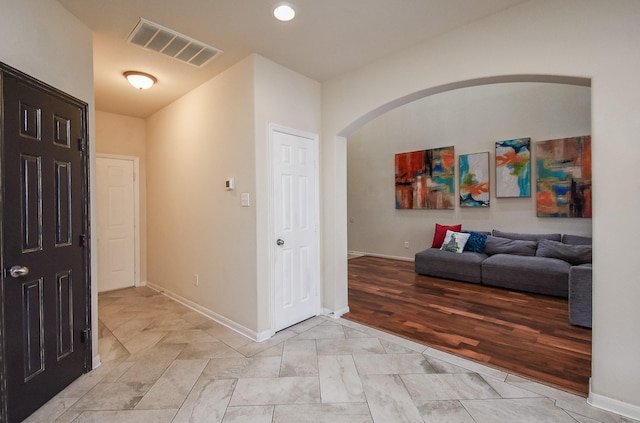 corridor with arched walkways, visible vents, and baseboards