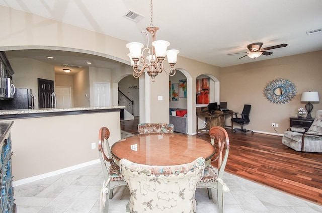 dining room featuring arched walkways, stairway, ceiling fan with notable chandelier, and visible vents