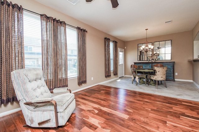 sitting room with baseboards, visible vents, wood finished floors, and ceiling fan with notable chandelier