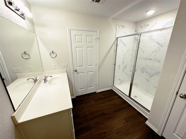 bathroom with a marble finish shower, visible vents, wood finished floors, and vanity