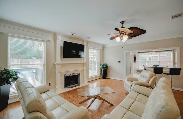 living area with a wealth of natural light, light wood-style flooring, a high end fireplace, and visible vents