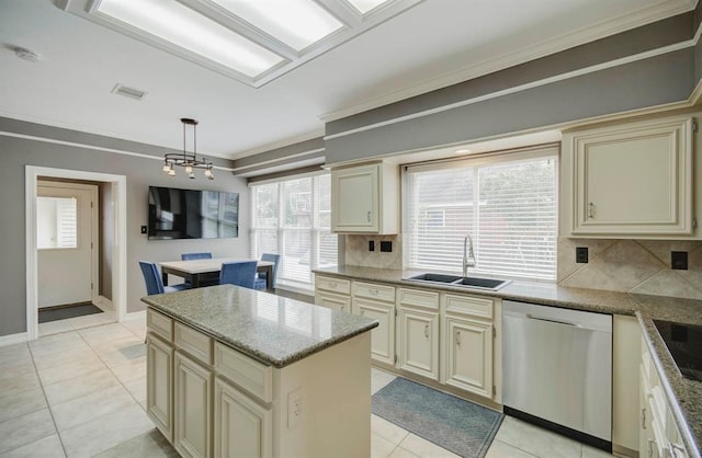 kitchen featuring cream cabinets, a sink, ornamental molding, stainless steel dishwasher, and a center island