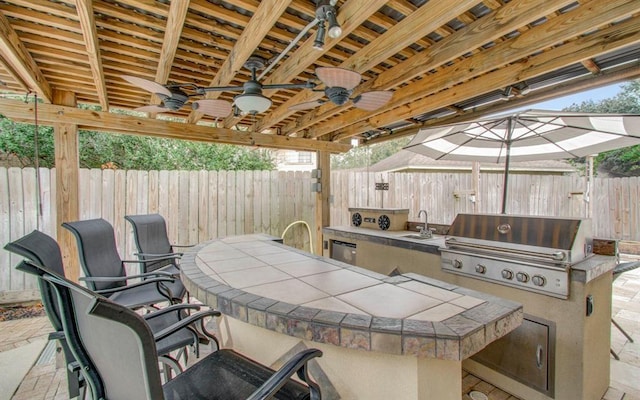 view of patio with exterior kitchen, a grill, a fenced backyard, and a sink