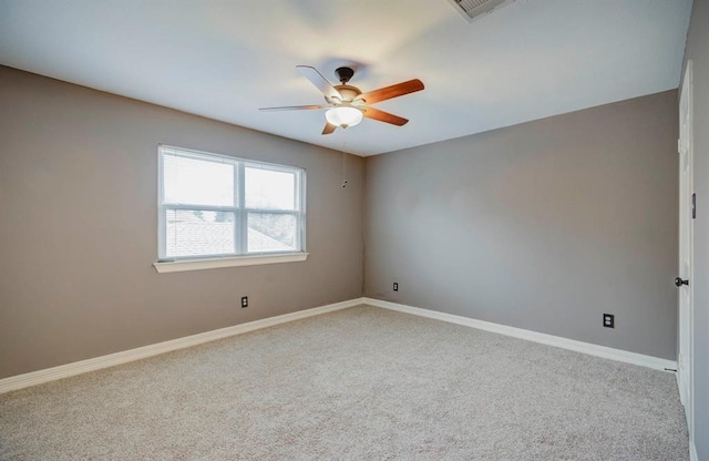 empty room with carpet flooring, ceiling fan, visible vents, and baseboards