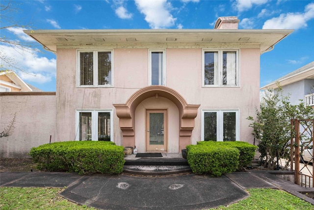 view of front of house featuring a chimney and stucco siding