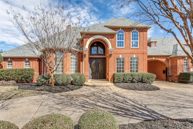 view of front of property with french doors, brick siding, roof with shingles, and a chimney