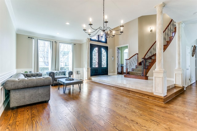 entrance foyer with french doors, crown molding, decorative columns, wood finished floors, and stairs