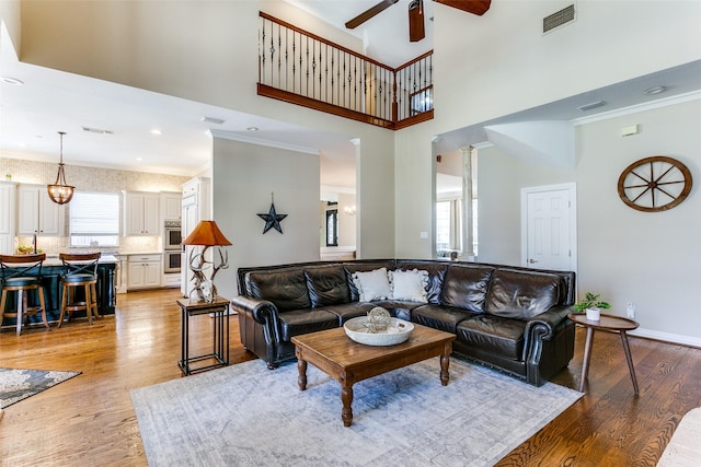 living area with visible vents, crown molding, and light wood finished floors