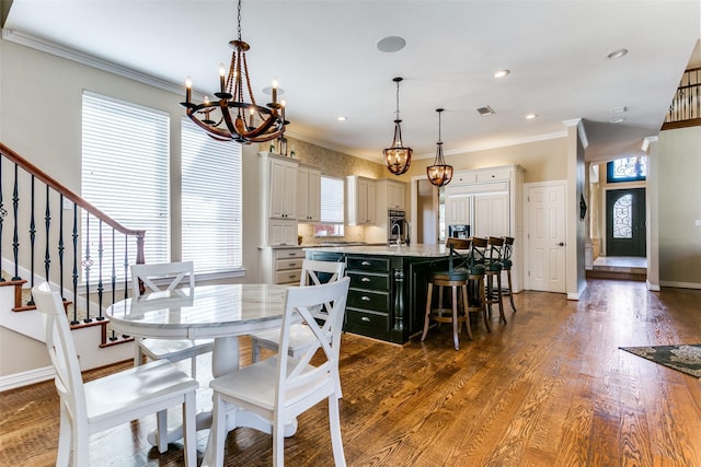 dining room featuring a healthy amount of sunlight, stairs, ornamental molding, and dark wood-type flooring