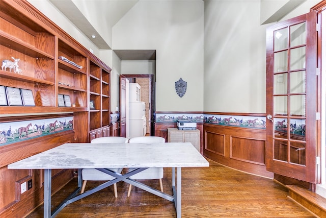 office space with high vaulted ceiling, wainscoting, and wood finished floors