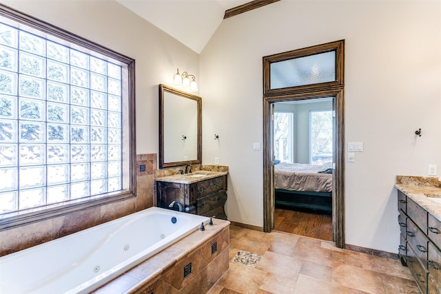 full bathroom with baseboards, connected bathroom, a jetted tub, vaulted ceiling, and vanity