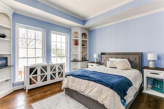 bedroom with ornamental molding, dark wood finished floors, and a raised ceiling