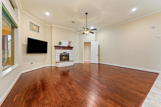 unfurnished living room featuring crown molding, baseboards, wood finished floors, and a stone fireplace