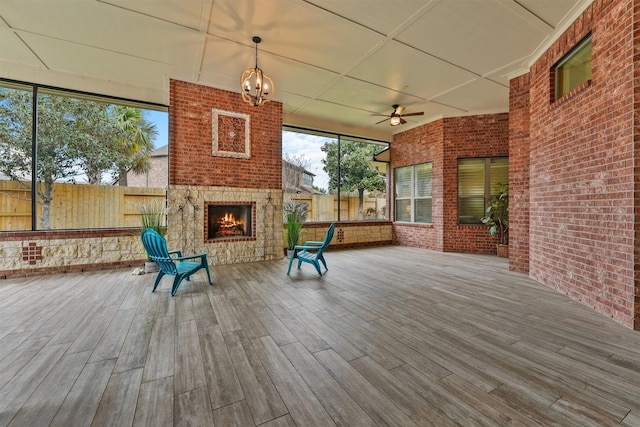 unfurnished sunroom featuring ceiling fan and an outdoor brick fireplace