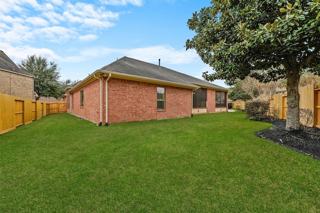 exterior space with brick siding, a yard, and a fenced backyard