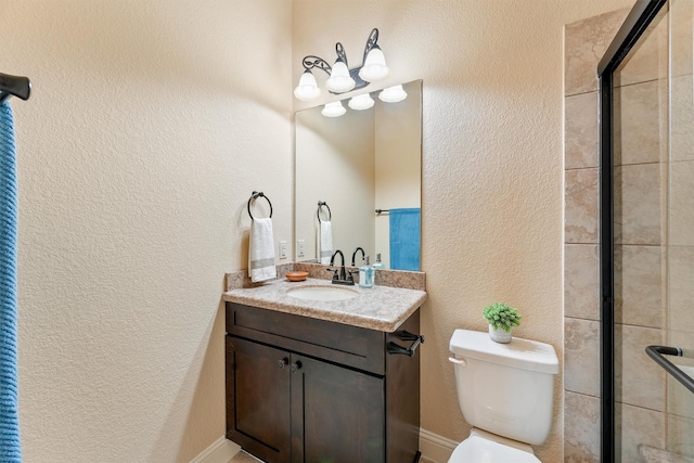 bathroom featuring a tile shower, a textured wall, vanity, and toilet