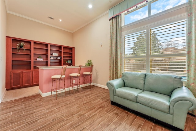 interior space with ornamental molding, a bar, wood finish floors, and visible vents