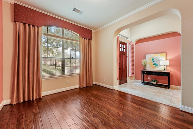 entryway featuring visible vents, arched walkways, wood finished floors, and ornamental molding