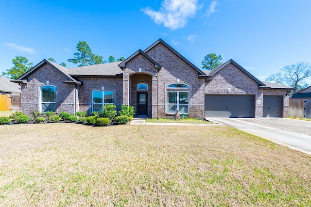 view of front of home with a garage, driveway, brick siding, fence, and a front yard