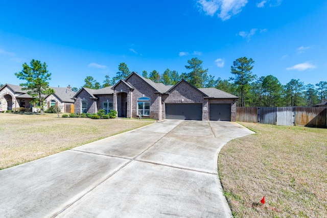 view of front of property featuring an attached garage, brick siding, fence, driveway, and a front lawn