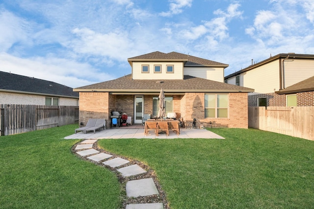 back of house with a patio, brick siding, a lawn, and a fenced backyard