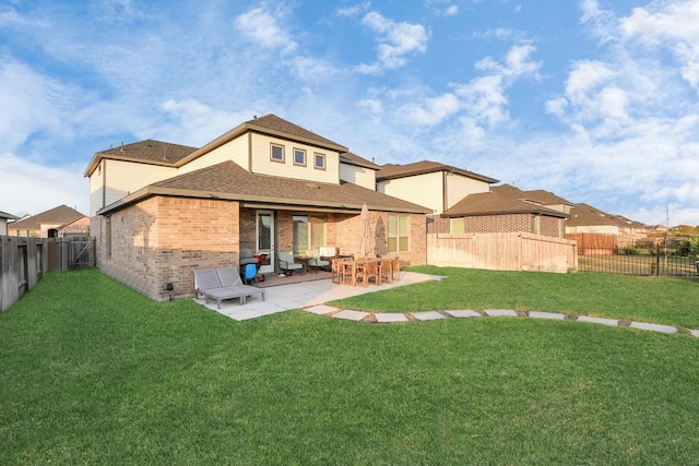 back of property with brick siding, a yard, roof with shingles, a patio area, and a fenced backyard