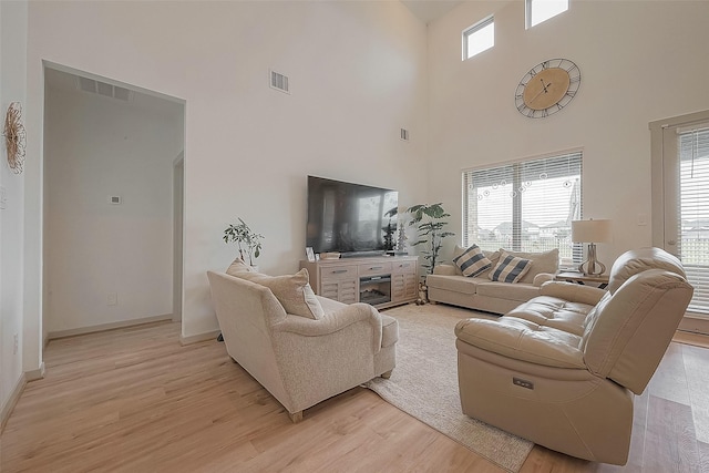 living room featuring light wood-style floors, baseboards, and visible vents